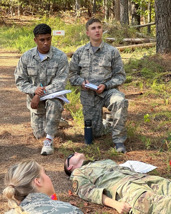 image of a few students kneeling while on a wooded trail looking at notebooks