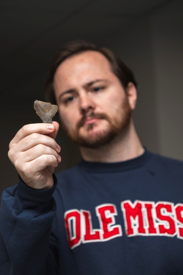 image of a student looking closely at an arrowhead