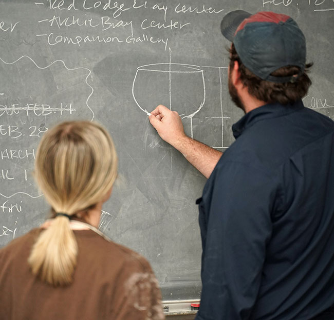 ray brown with student writing on chalkboard