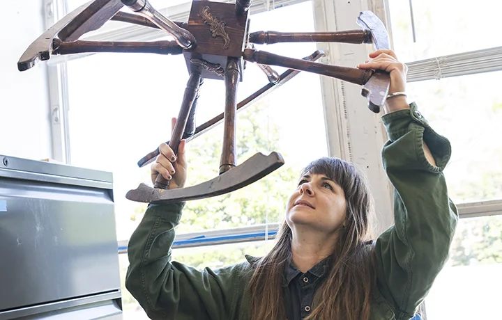person holding up wooden sculpture.