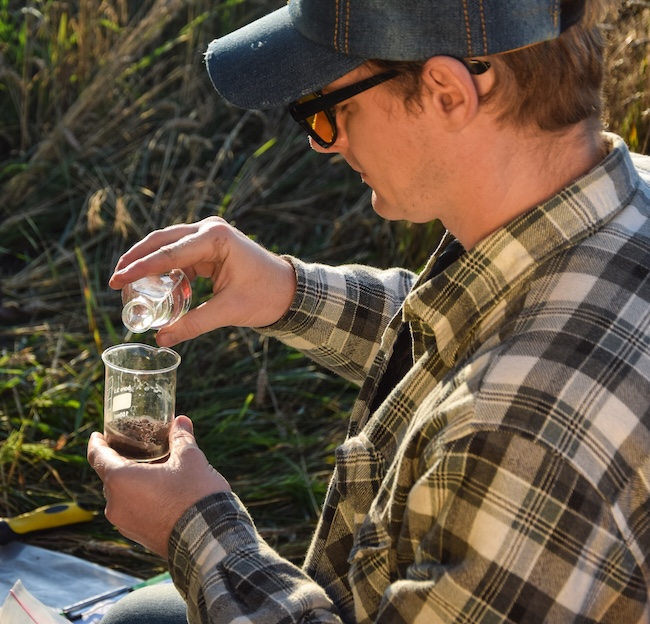 Male agronomy specialist testing soil sample outdoors