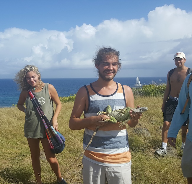 male student in the caribbean holding an iguana.