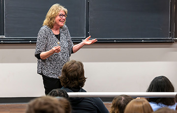 female professor standing and teaching in front of students