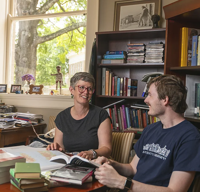 professor and student looking and talking with book opened