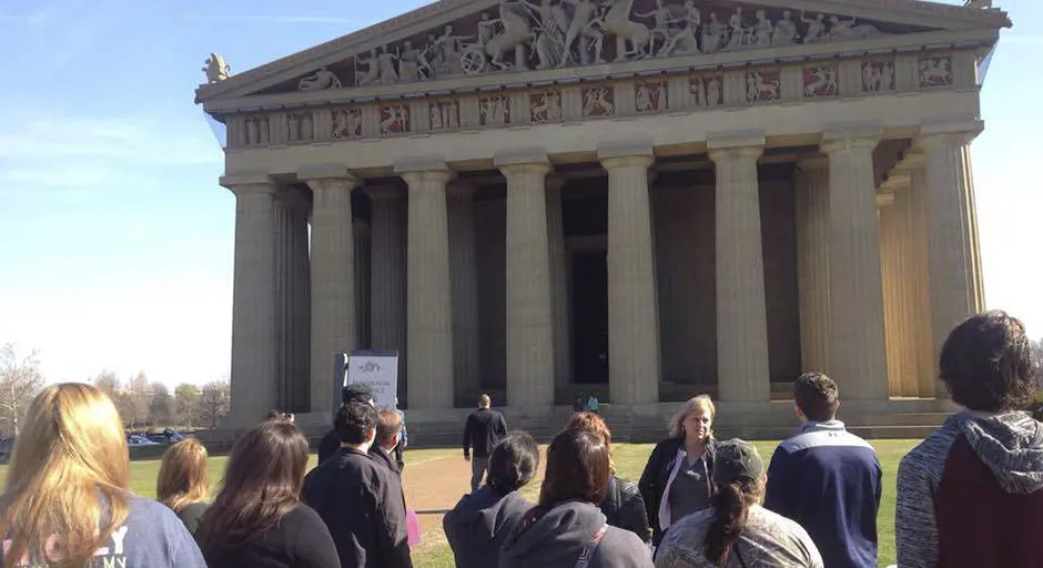 Group of students and professor in front of replica of the Parthenon