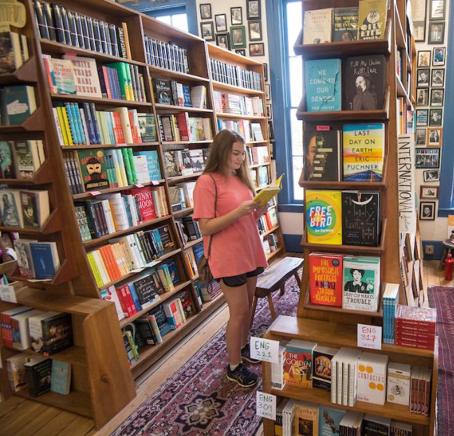 student between bookshelves at local bookstore Square Books