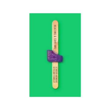 Popsicle stick with mostly melted purple popsicle. Bright green background