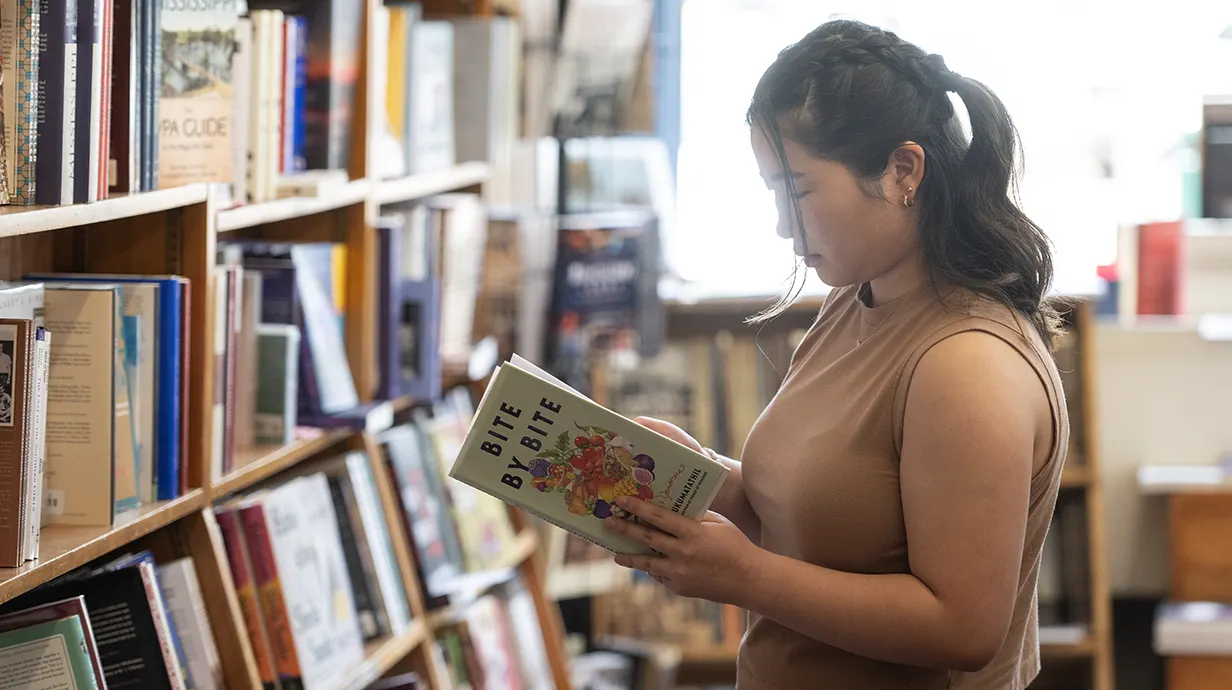 Student reads book standing in shelves at local store Square Books