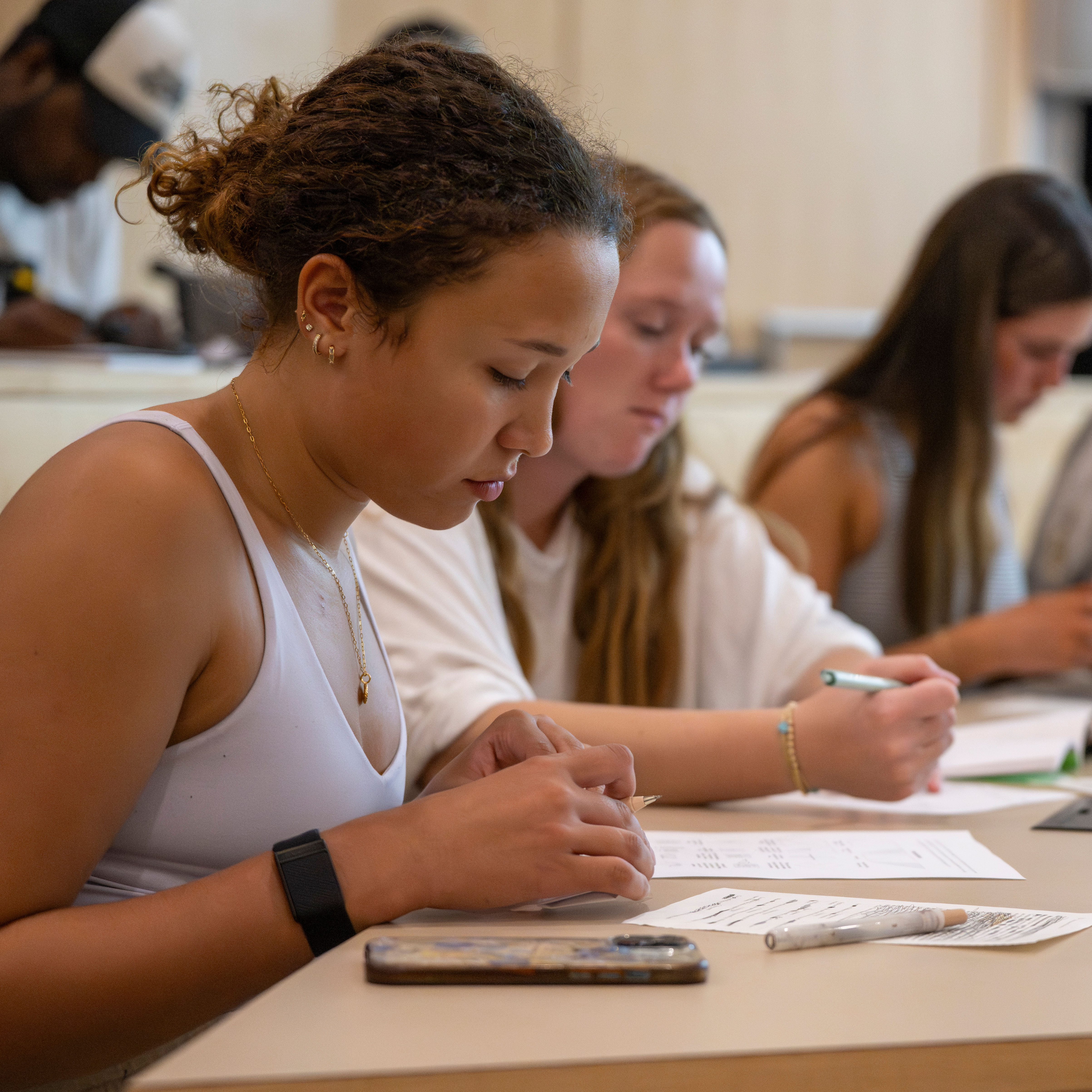 Students sit at lecture-hall tables during class time and work