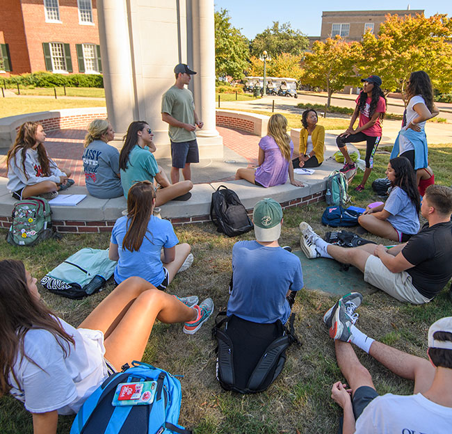 Students and a teacher sitting around outside talking