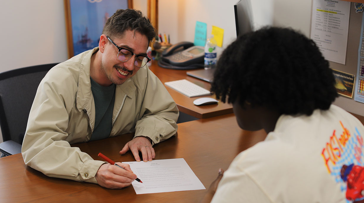 advisor sitting at desk with student