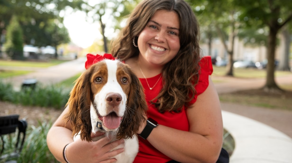 image of a student and a dog sitting outside in the Circle of UM campus