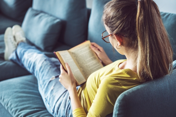 image of a young girl reading a book while seated on a couch