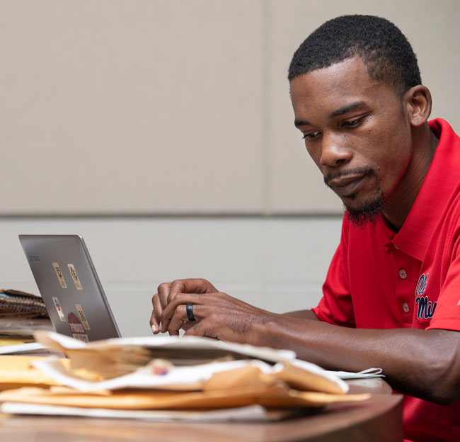 student working at a desk with a computer and papers