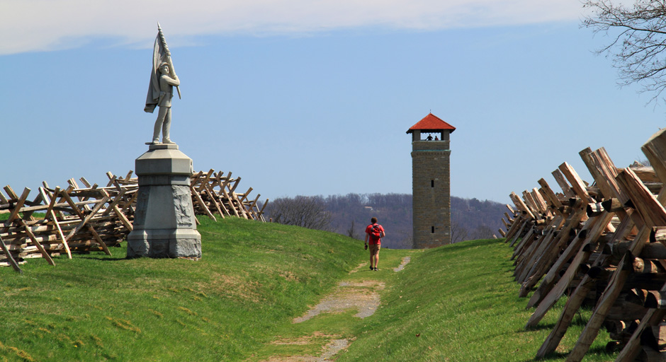 man walking down lane with grass and wood barrier on either side