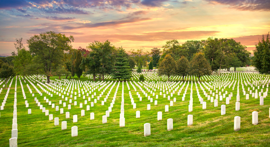 headstones on a grassy field with a sunset in the background