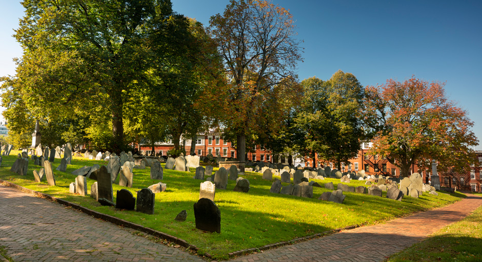 headstones on a grassy field with a building in the background