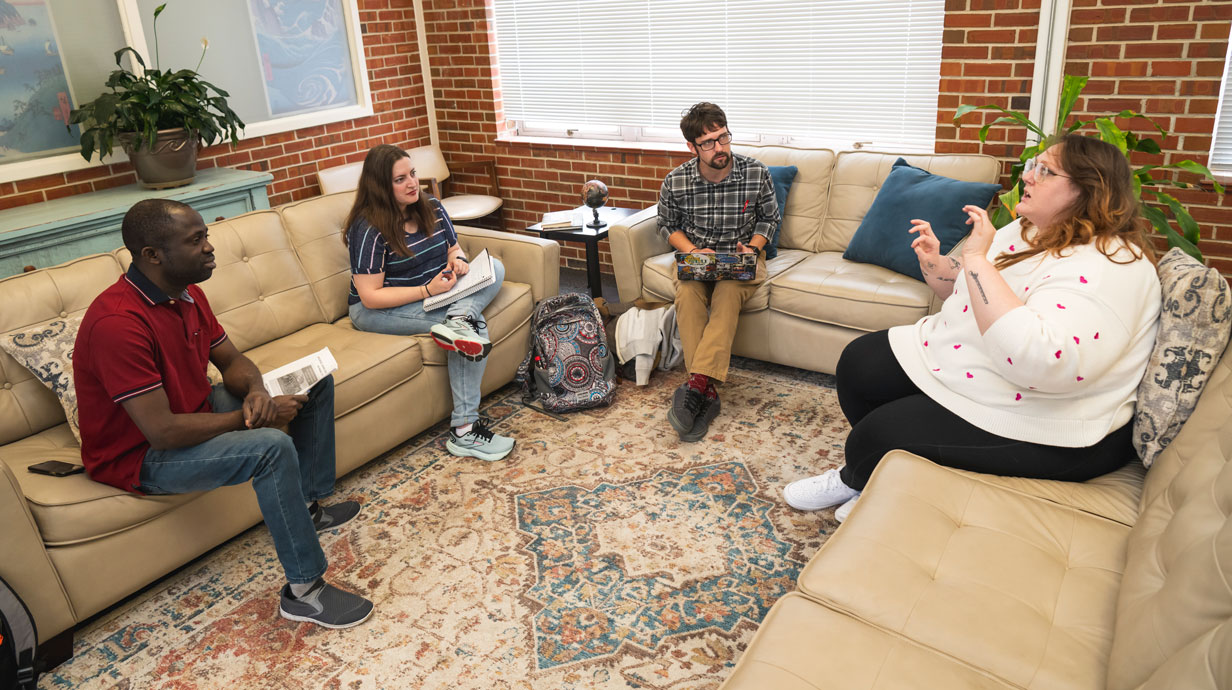 four history graduate students sit on couches and have a discussion