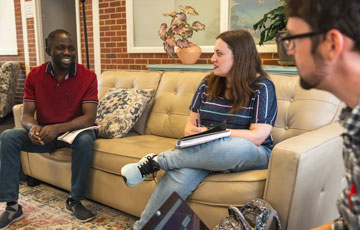 three students sit on a couch and have a discussion