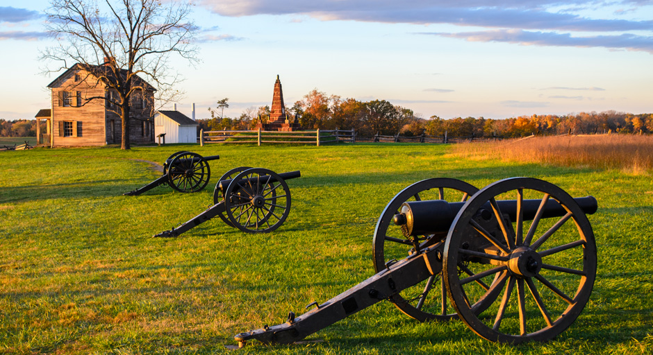 cannons on a grassy plain with a building in the background