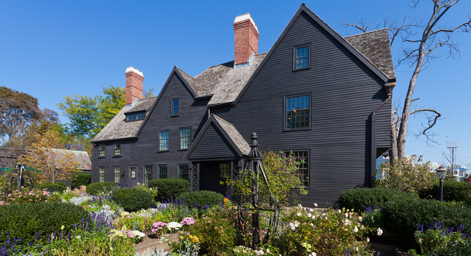 black house on a sunny day with flowers growing in the front yard