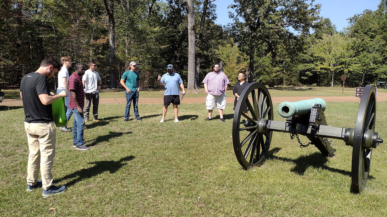people standing around old canon