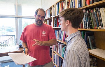 professor and student stand in library and talk