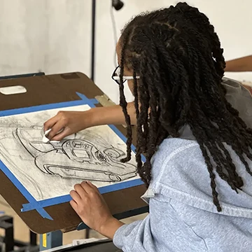 a girl sketches in charcoal