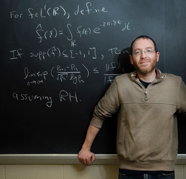 professor standing in front of chalk board with math on it