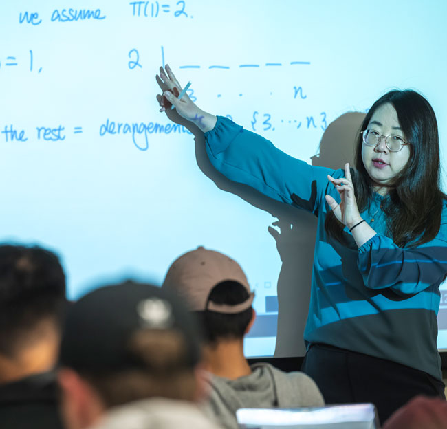 female professor pointing to a projector and talking with a female student