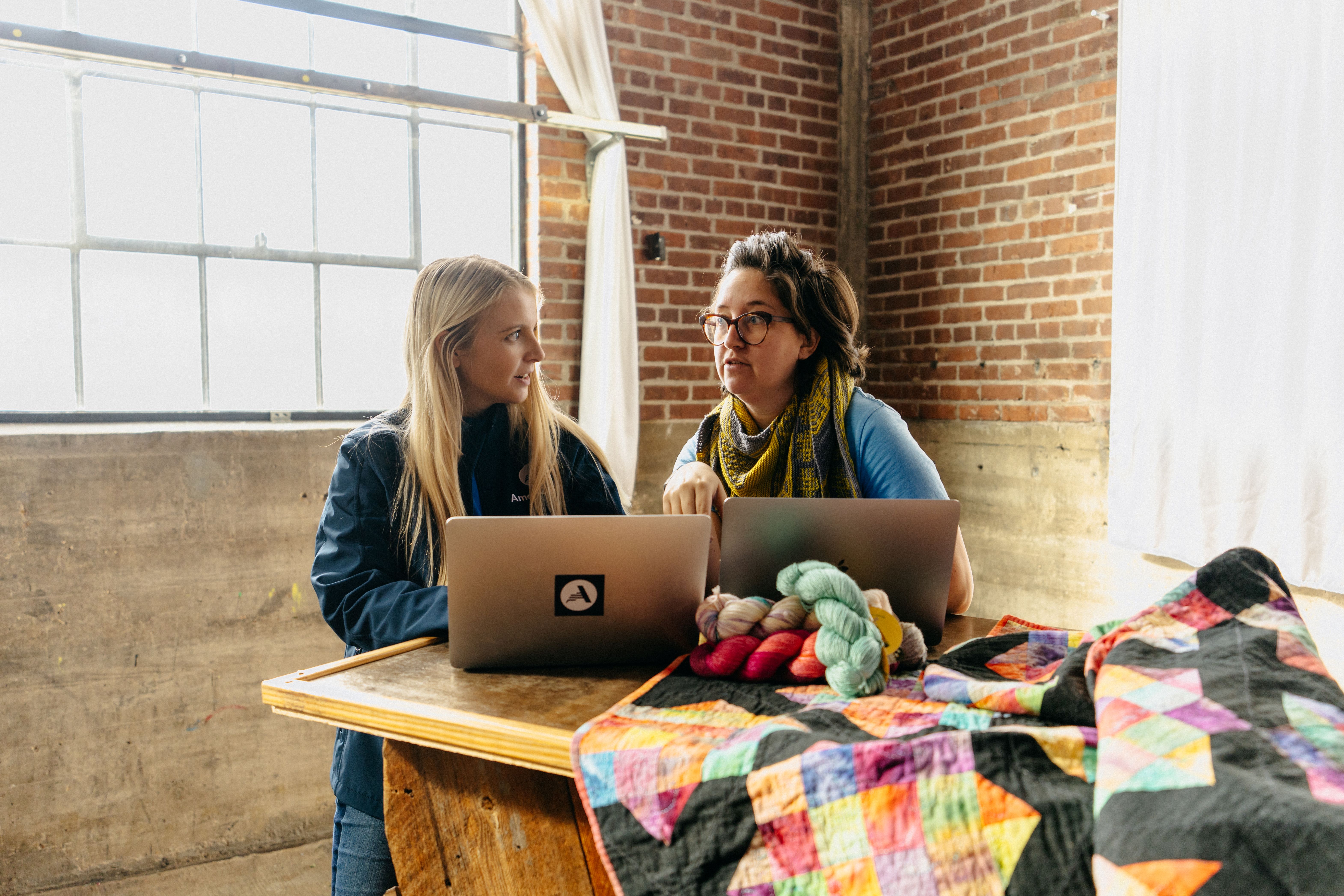 An AmeriCorps member talks with a community member about her quilt