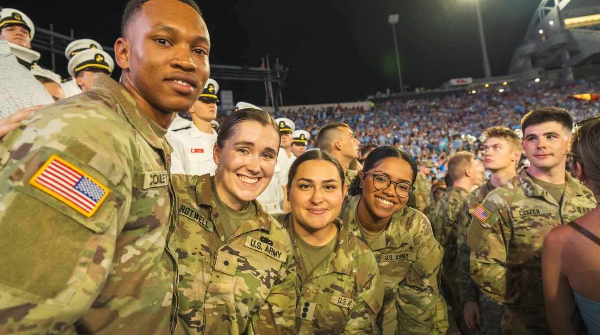 group of students smiling together in the stands of the football field