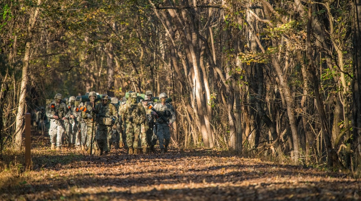 image of cadets marching in formation through the woods with face paint and uniforms