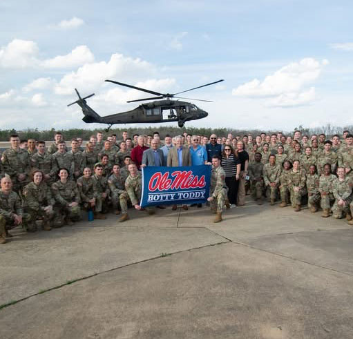 image of rotc students holding a flag with a helicopter in the background