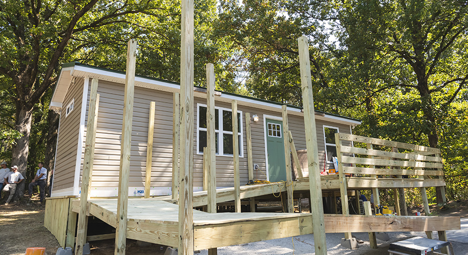 A new house sits among trees with a deck nearly complete in front.