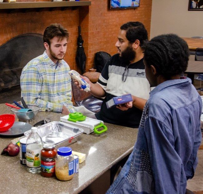 image of three people seated around a large table looking at food items