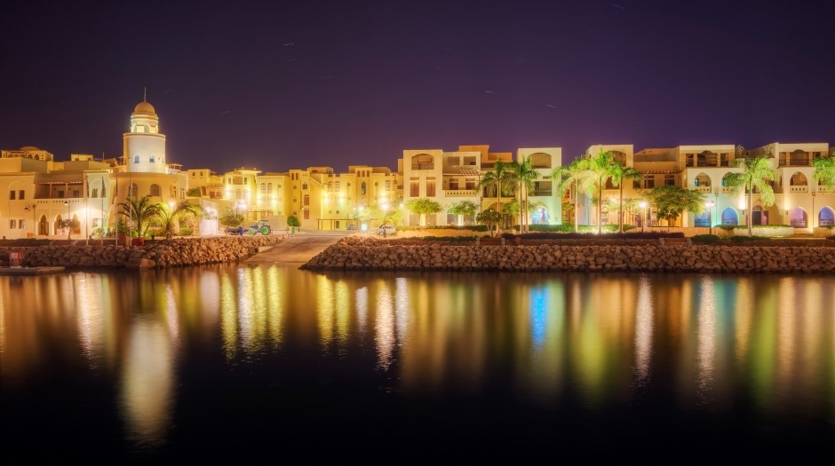 night photo of a resort near the ocean with lights reflected in the water