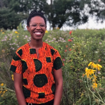 portrait photo of Qua Sayles with flowers and plants behind her