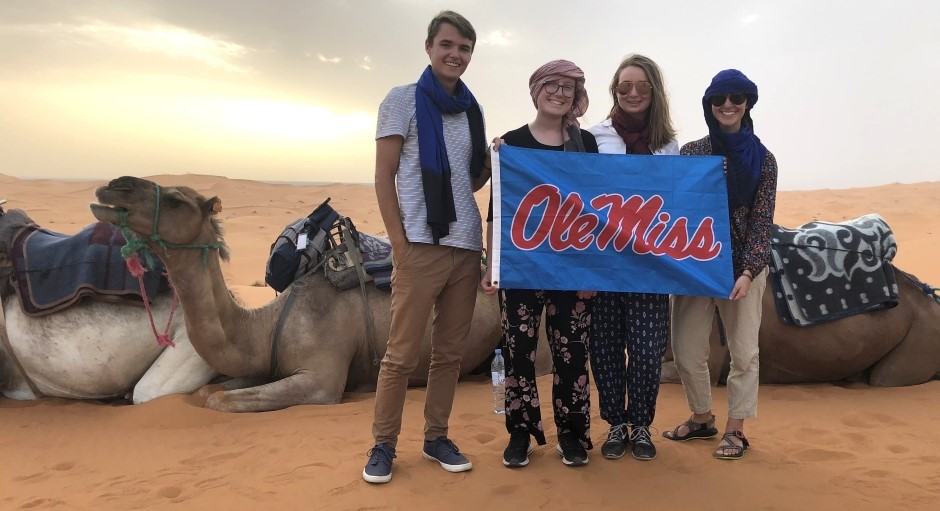 students holding an Ole Miss banner while in the desert with camels in the background