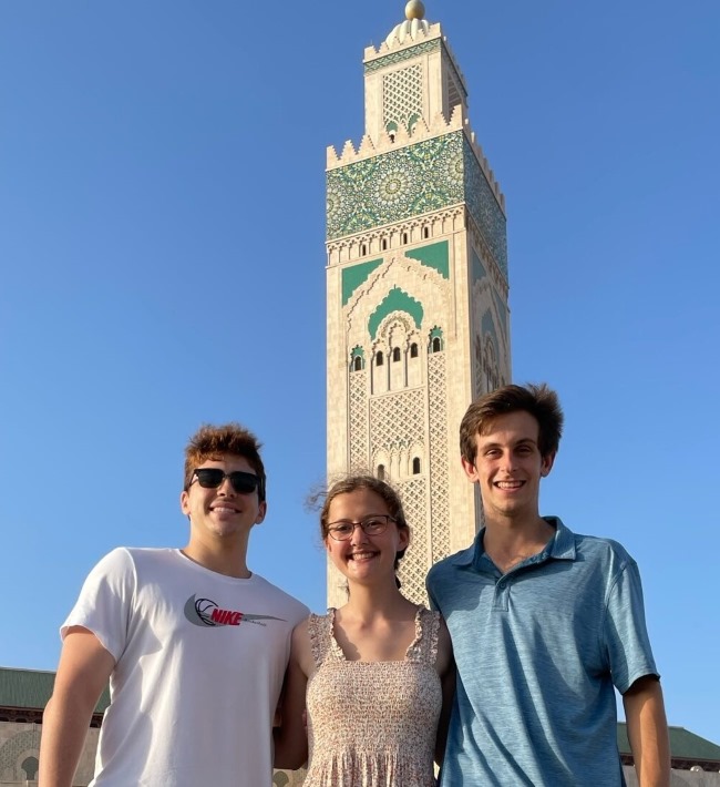 image of three students looking at the camera with a mosque tower in the background