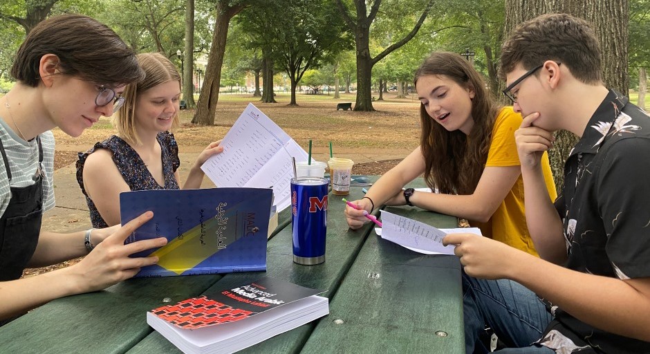 students studying together outside on a picnic table