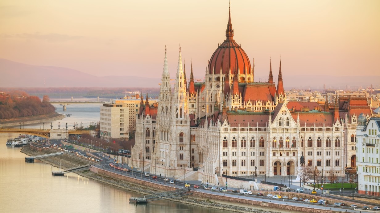 image of a large parliamentary building with elaborate architecture along a river in the Hungarian capital city