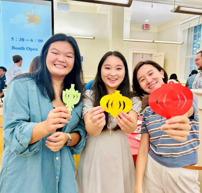 image of three students holding paper lanterns to the camera