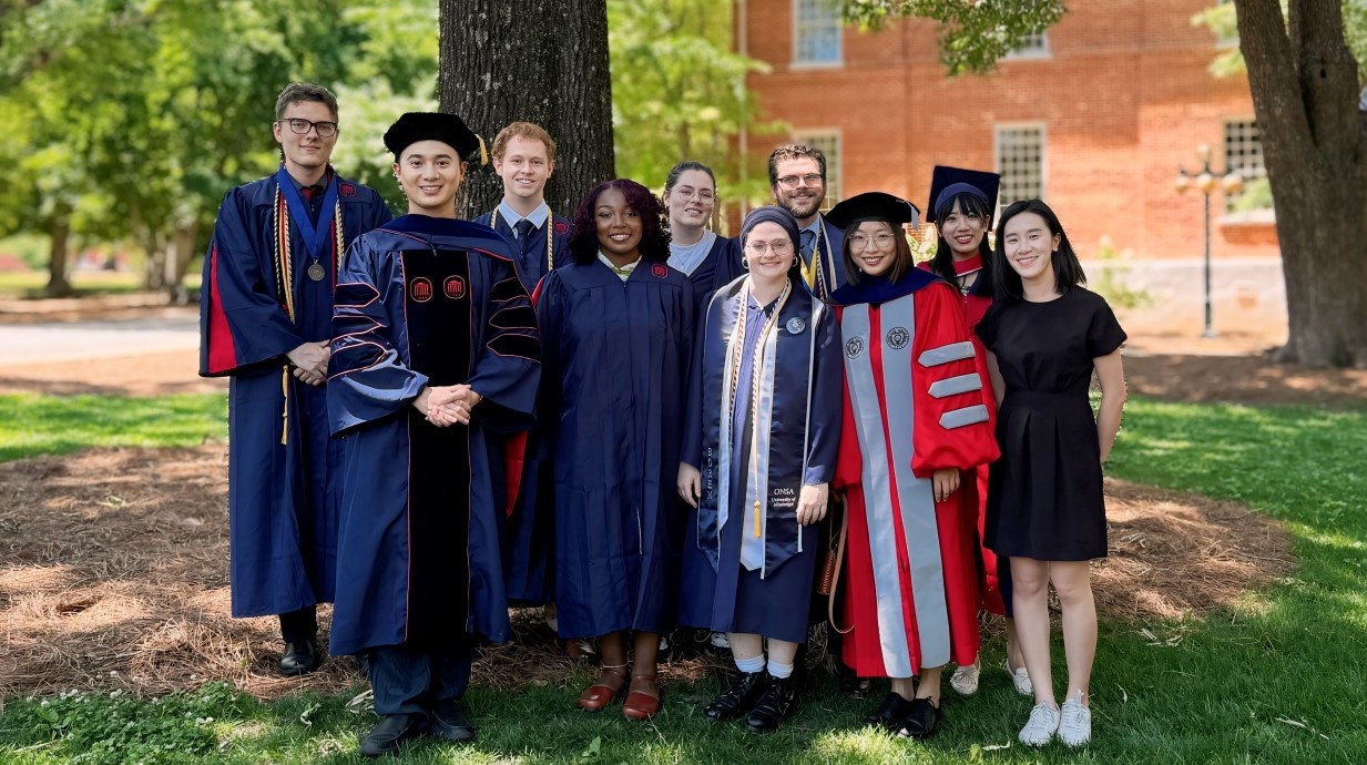 group of students and professors in graduation robes standing together at graduation