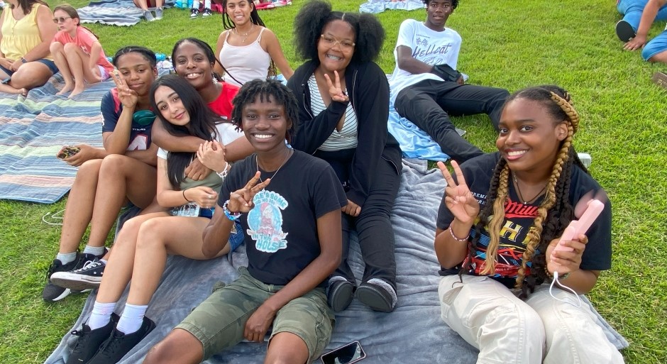 group of students seated on a blanket on a grassy hill