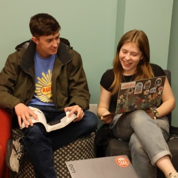 two students are seated together and looking at a computer 