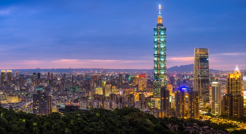 aerial view of an evening over Taipei, Taiwan with tall buildings lit up and mountains in the foreground