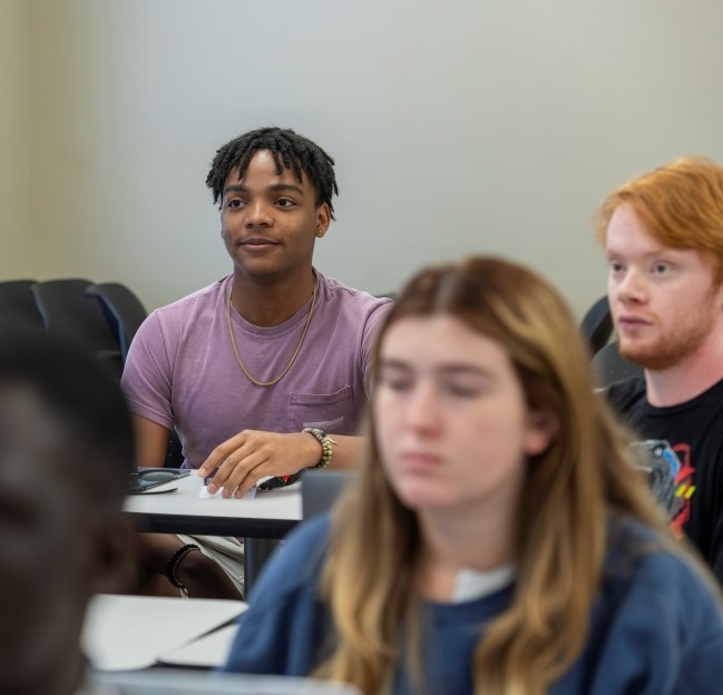 image of a student smiling in class as he looks towards the front of the class