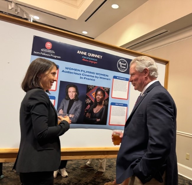 image of a faculty member talking with the UM Chancellor while standing in front of her research poster