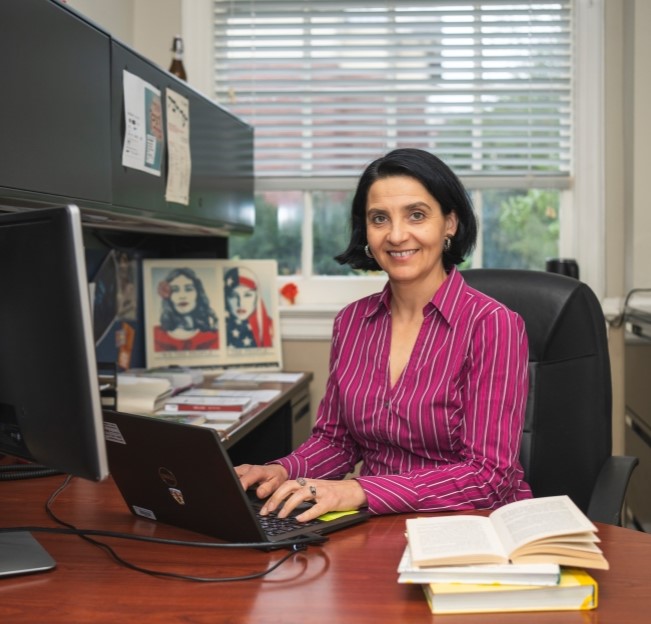 image of professor seated at her desk ad typing on her computer